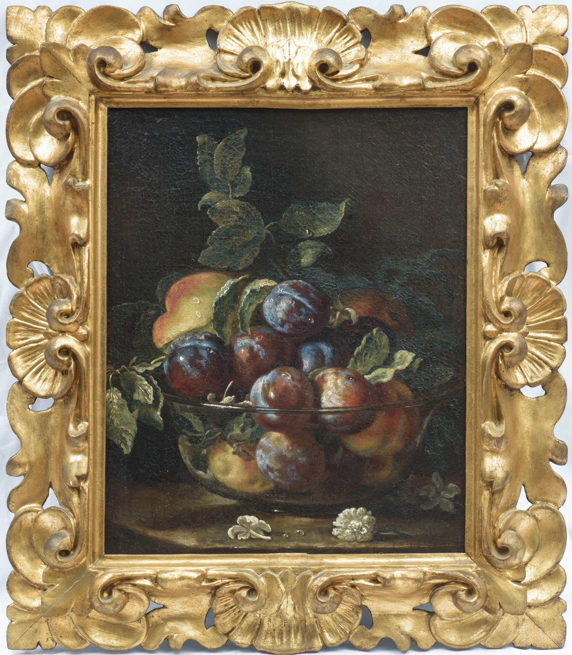 Composizione di frutta con pesche susine e una coppa in vetro