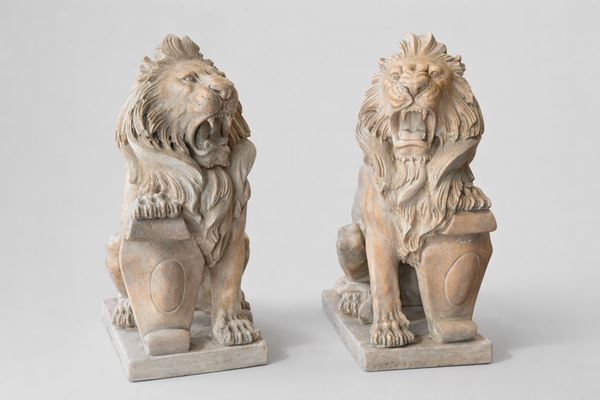 Coppia di sculture raffiguranti leoni reggenti un cartiglio 