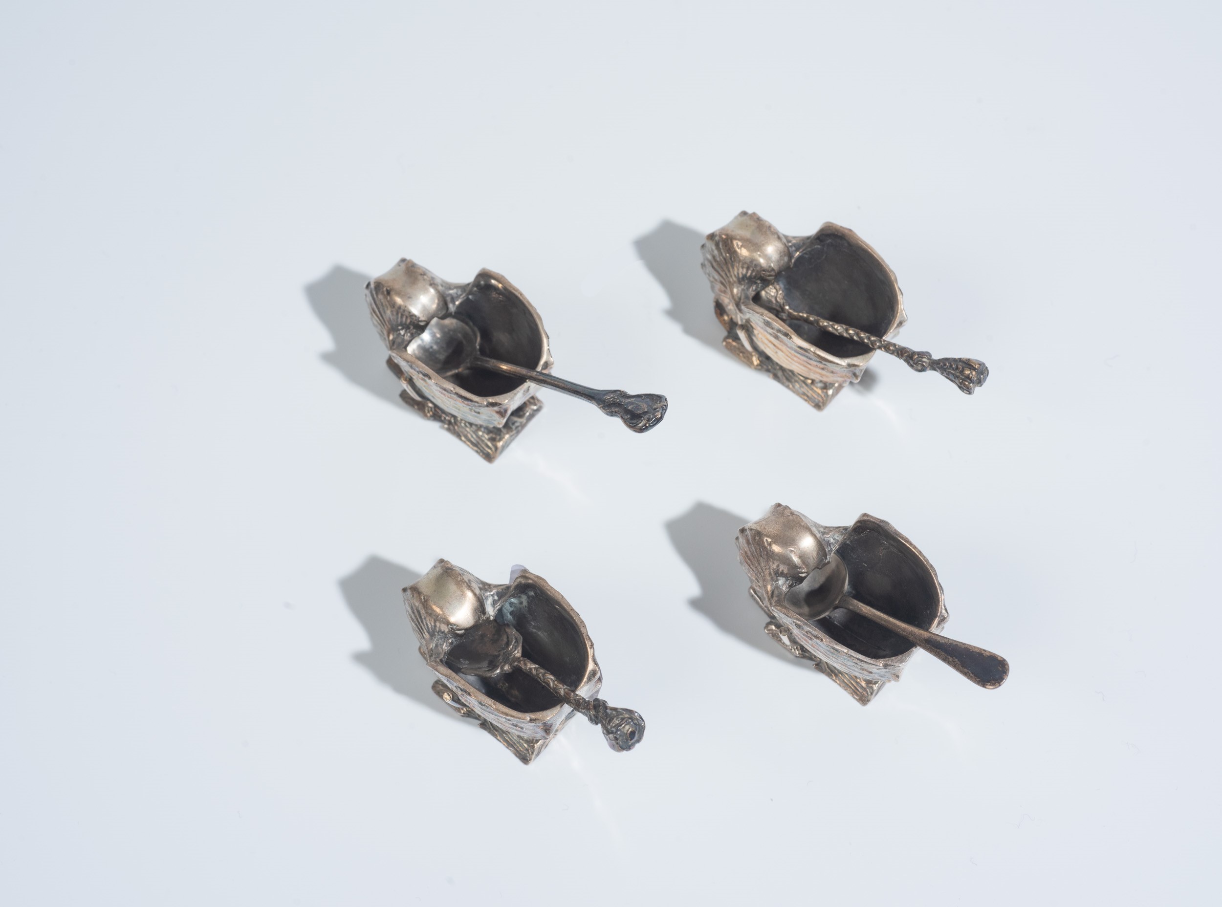 Set di quattro saliere in metallo argentato con quattro cucchiaini, XX secolo